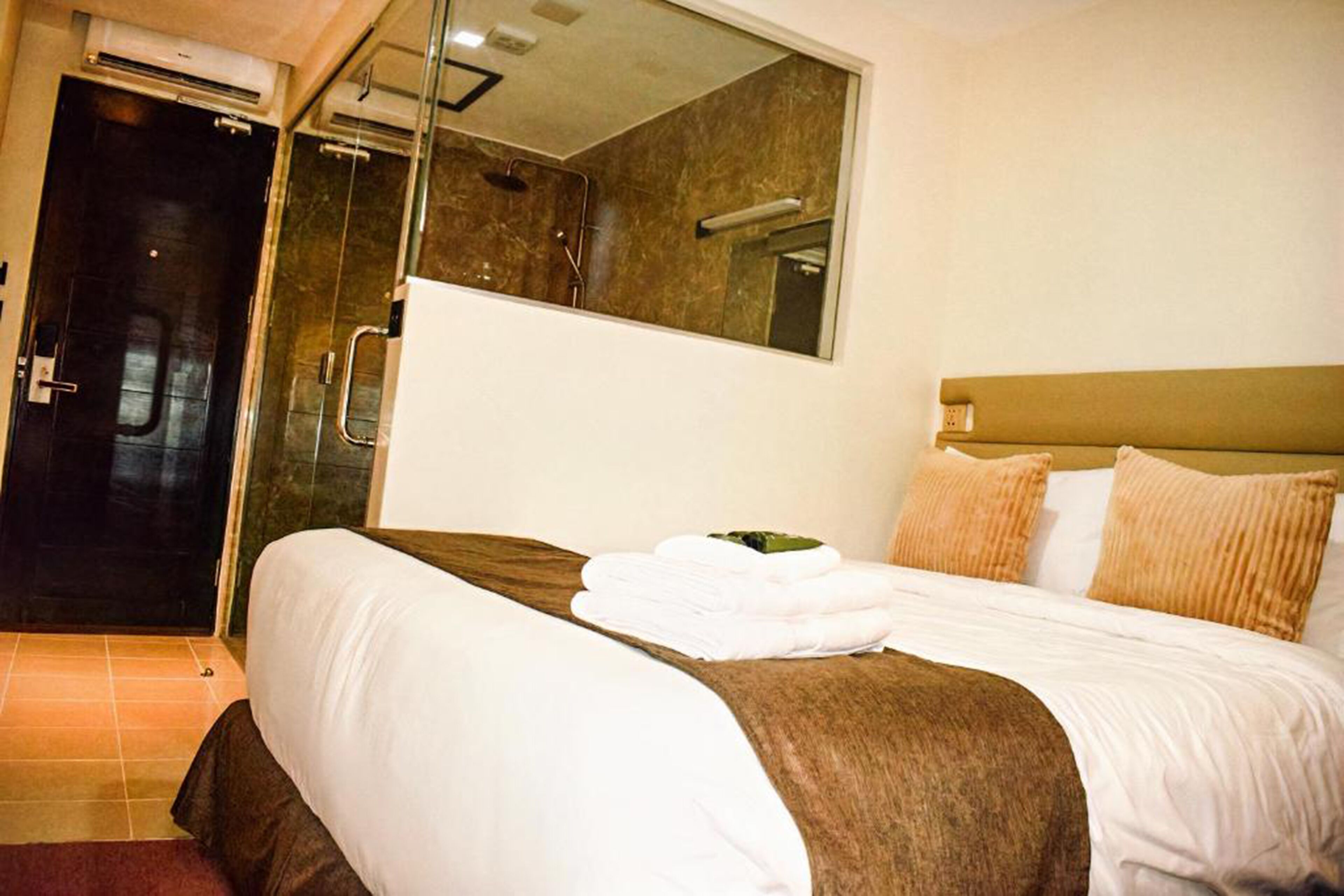 Ein Hotelzimmer mit einem großen Bett, einer Duschkabine und einem Spiegel an der Wand.