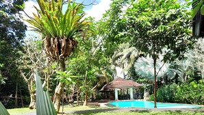 A garden with a pool, a gazebo, and various trees. - Panorama Hotel Ubud (Ubud)