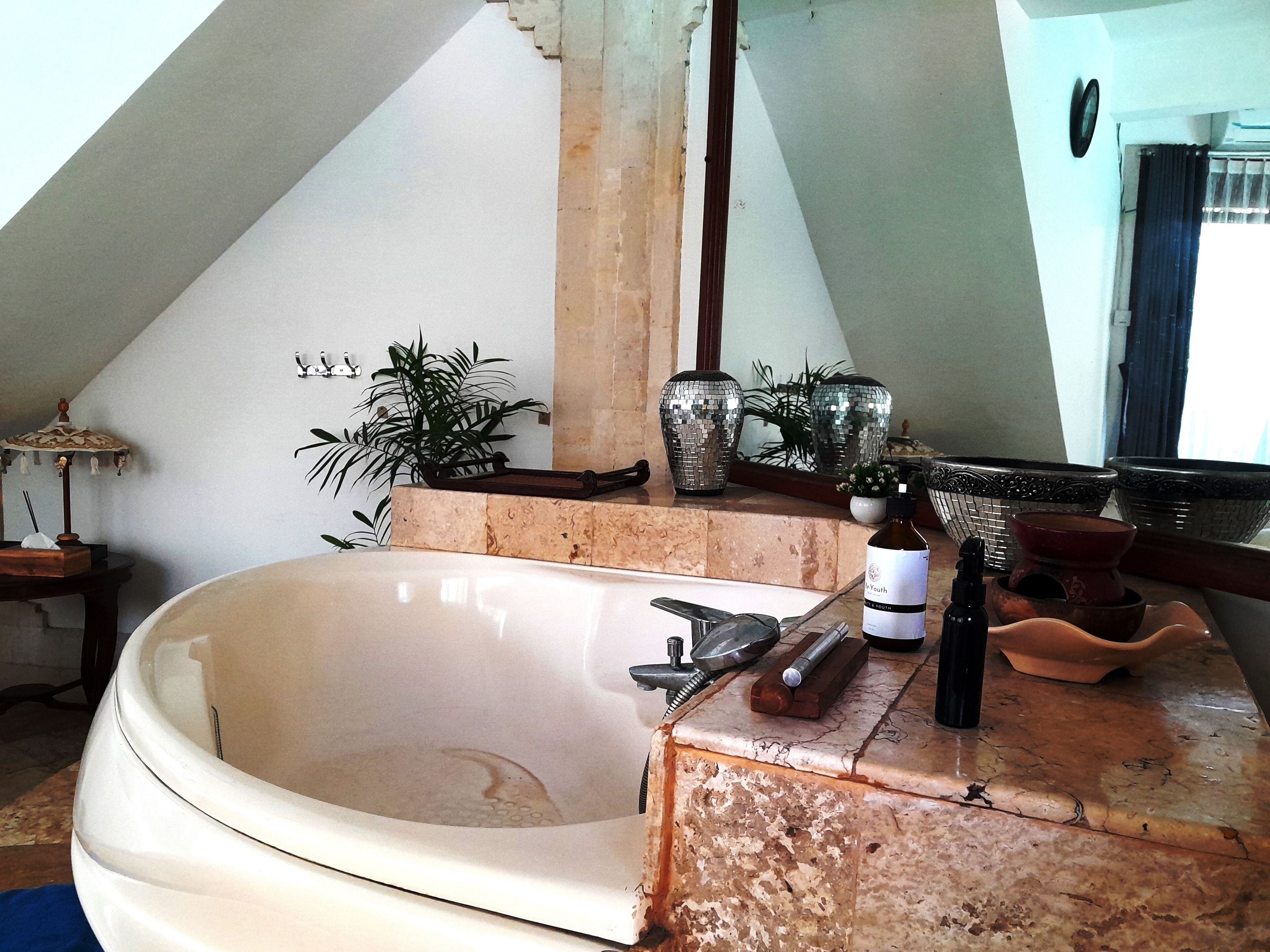 Une salle de bain avec une grande baignoire, un miroir et un lavabo équipé de divers produits de toilette.