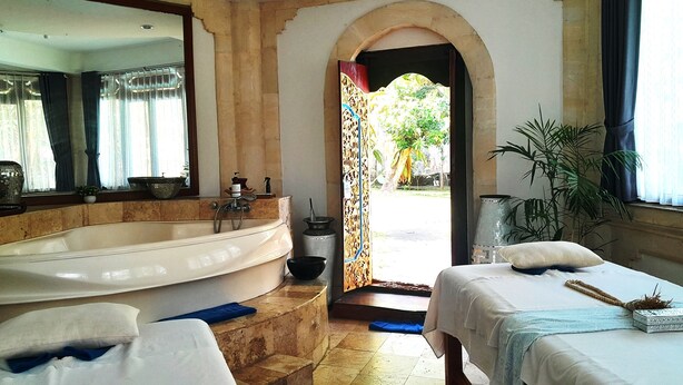 A hotel room with a large bathtub, two beds, a mirror, and a view of the outdoors. - Panorama Hotel Ubud (Ubud)