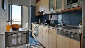 Una cocina moderna con armarios de madera, un microondas integrado y un lavamanos de acero inoxidable.