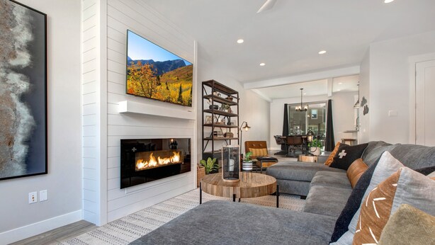 A modern living room with a fireplace, a large TV, and a cozy seating area. - Luxury Townhome at Wasatch Springs - Black Rock Ridge + Ski Park City (Heber City)