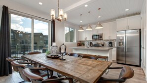 A modern kitchen with white cabinets, stainless steel appliances, and pendant lighting. - Luxury Townhome at Wasatch Springs - Black Rock Ridge + Ski Park City (Heber City)
