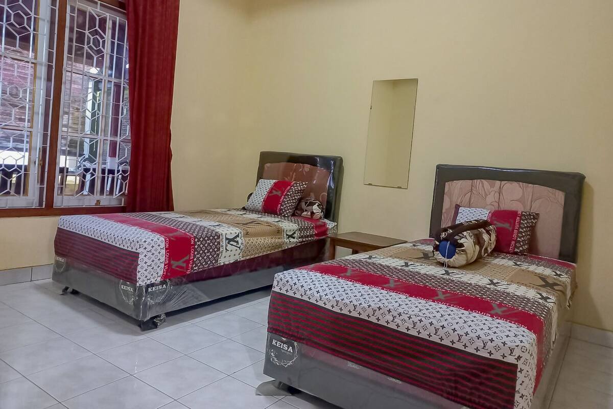 A hotel room with two beds, a window with a view, and an air conditioning unit on the wall.