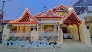 A traditional house with a tiled roof, a white fence, and potted plants in front. - Rumah Kost Nakula (Banyuwangi)