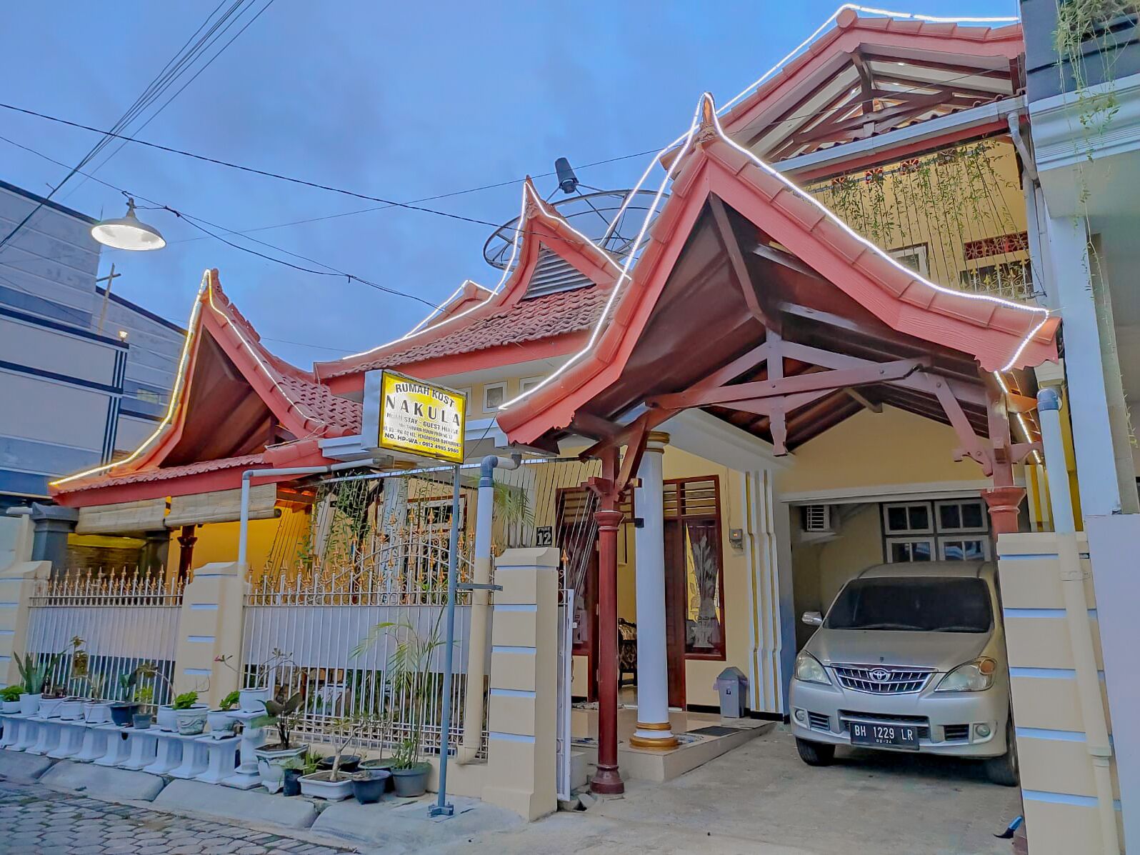 A traditional house with a red roof and a signboard advertising a guesthouse.