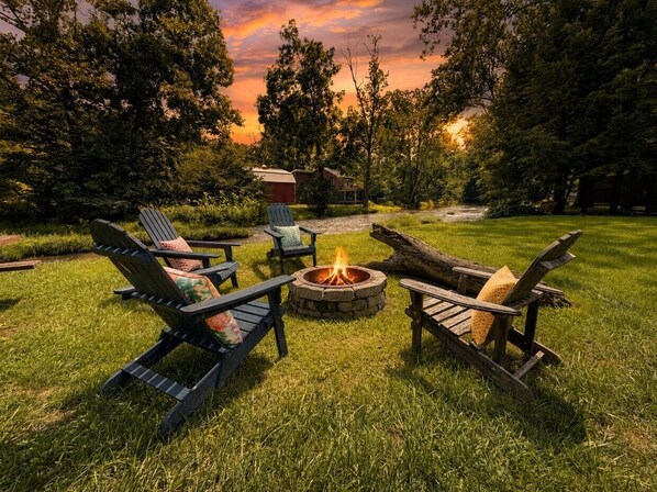 A fire pit with chairs arranged around it in a grassy outdoor area.