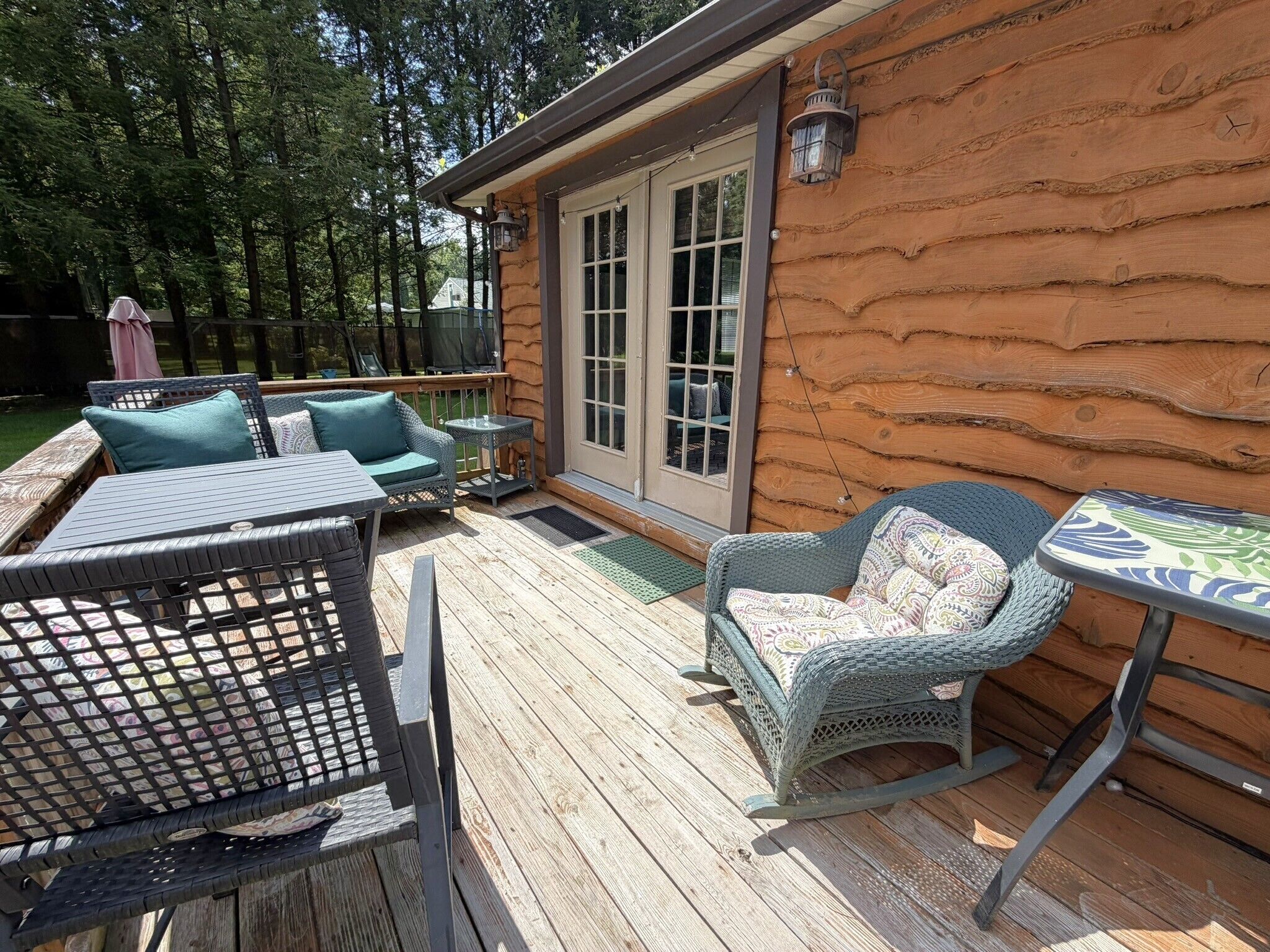 Um deck de madeira com móveis de exterior, incluindo cadeiras e uma mesa.