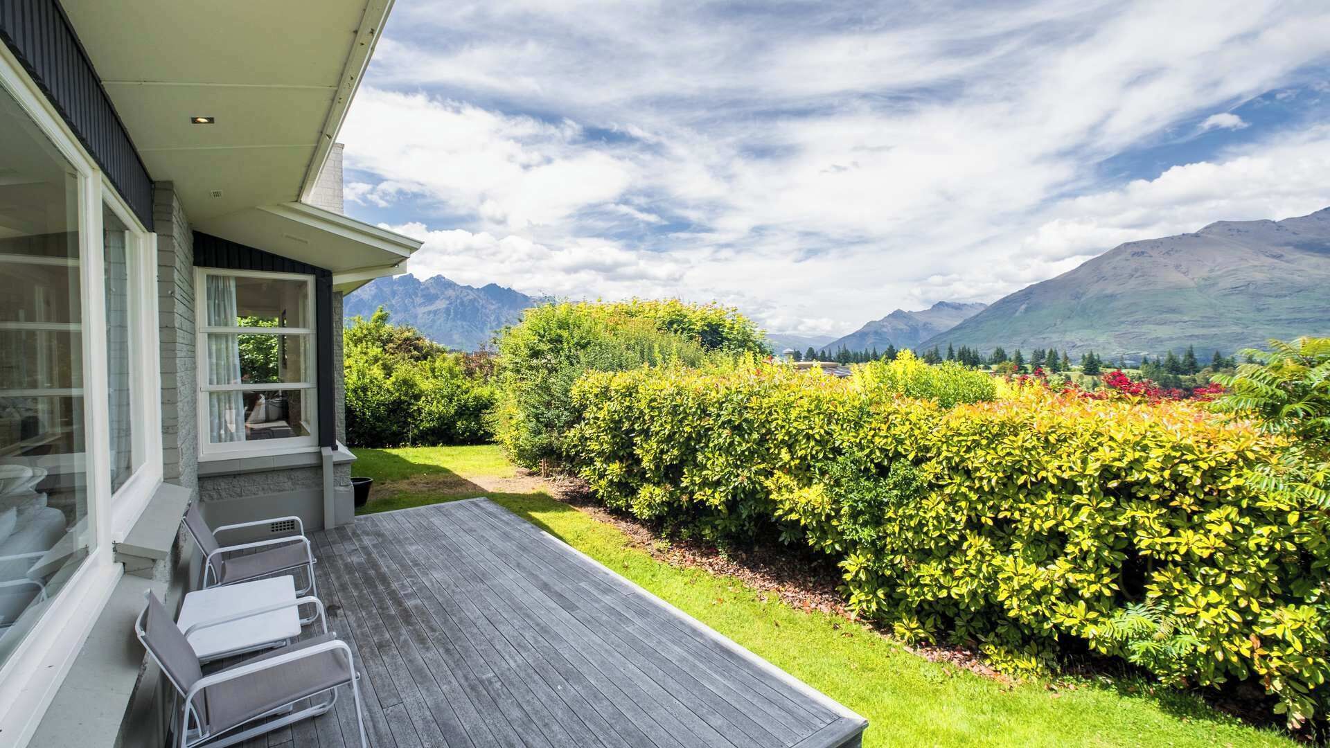A modern outdoor patio with a view of mountains and a well-maintained garden.