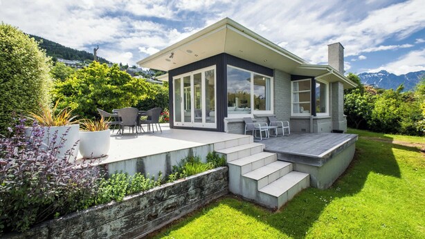 Une maison moderne dotée d’un patio, d’un espace salon extérieur et offrant une vue sur les montagnes.