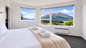 Une chambre d’hôtel avec un grand lit, deux fenêtres donnant sur la montagne et un radiateur.