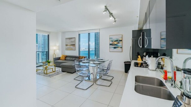 A modern apartment with a dining area, kitchen, and living room.