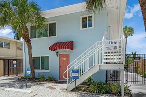 A two-story building with a red awning, a staircase, and a gated entrance.