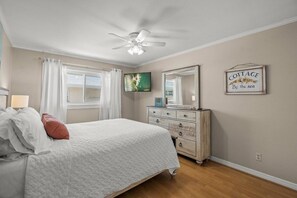 A bedroom with a bed, a dresser, a ceiling fan, a television, and a wall-mounted sign. - Siesta Key | Bay Patio & Dock | Free Activities (Sarasota)