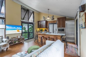 A spacious living area with a large TV, wooden flooring, and a cozy seating arrangement. - Cozy Cottage on the Beach | Steps to SK Village (Siesta Key)