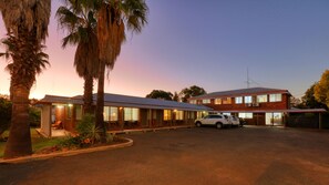 Un motel à deux étages, doté d’un toit plat, de grandes fenêtres et d’un espace de stationnement.