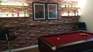 A room with a pool table, two framed pictures on the wall, and shelves with bottles. - Executive Lakeside 4 Bed Townhouse (Milton Keynes)