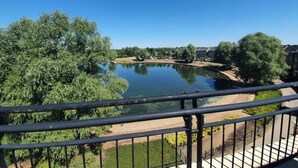 A view of a calm lake with surrounding greenery and buildings. - Executive Lakeside 4 Bed Townhouse (Milton Keynes)