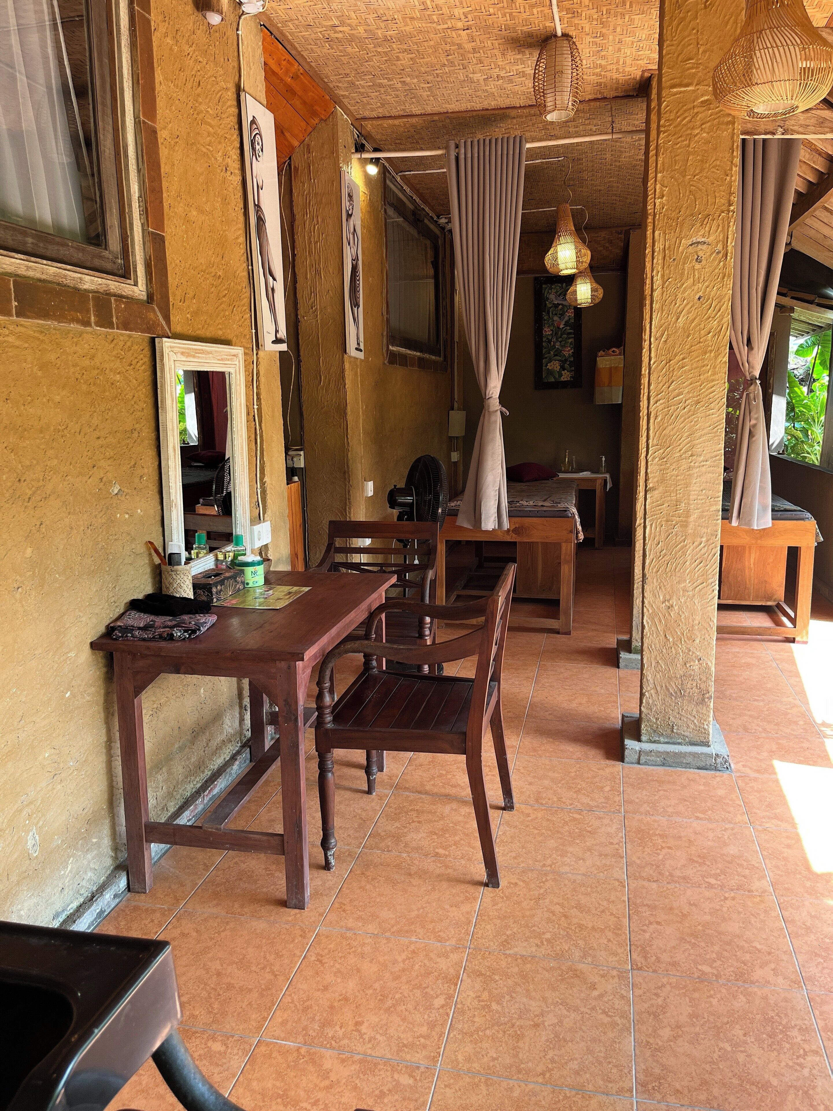 A room with a wooden table and chairs, a mirror, and a fan.