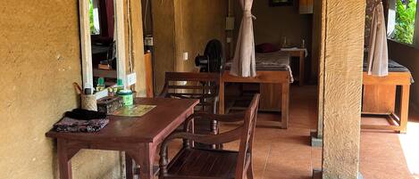 A room with a wooden table and chairs, a mirror, and a fan.
