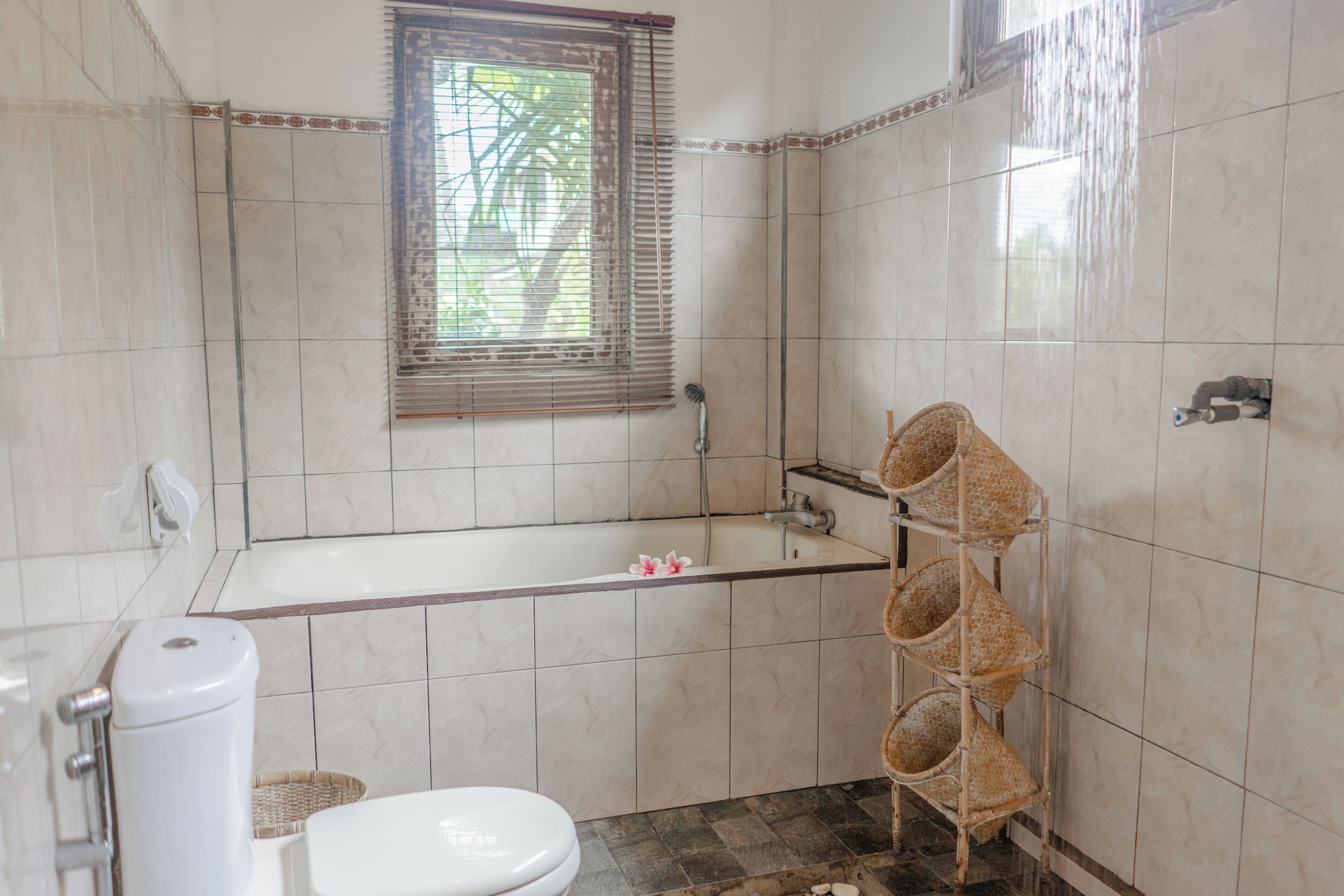 Ein Badezimmer mit Badewanne, Toilette und einem Fenster mit Jalousien.