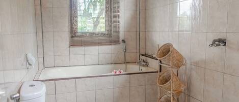Ein Badezimmer mit Badewanne, Toilette und einem Fenster mit Jalousien.