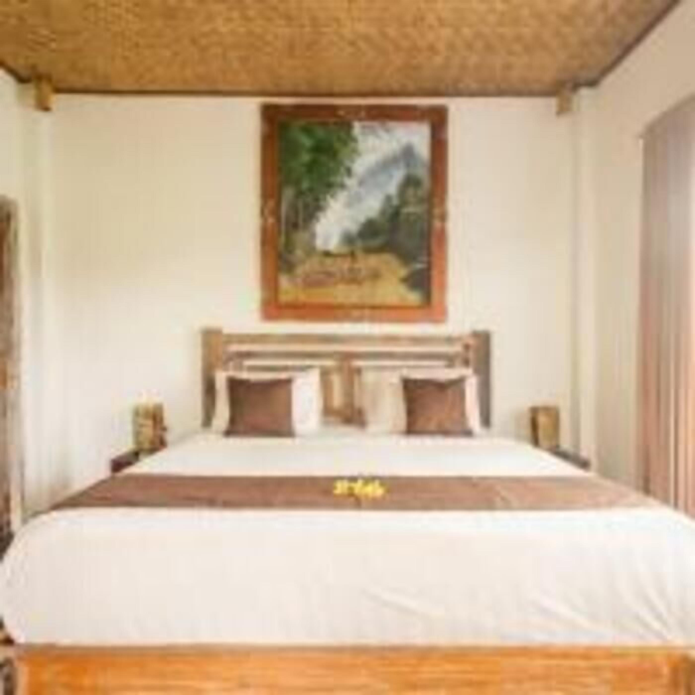 A bedroom with a wooden bed, a painting on the wall, and a bedside table with a lamp.
