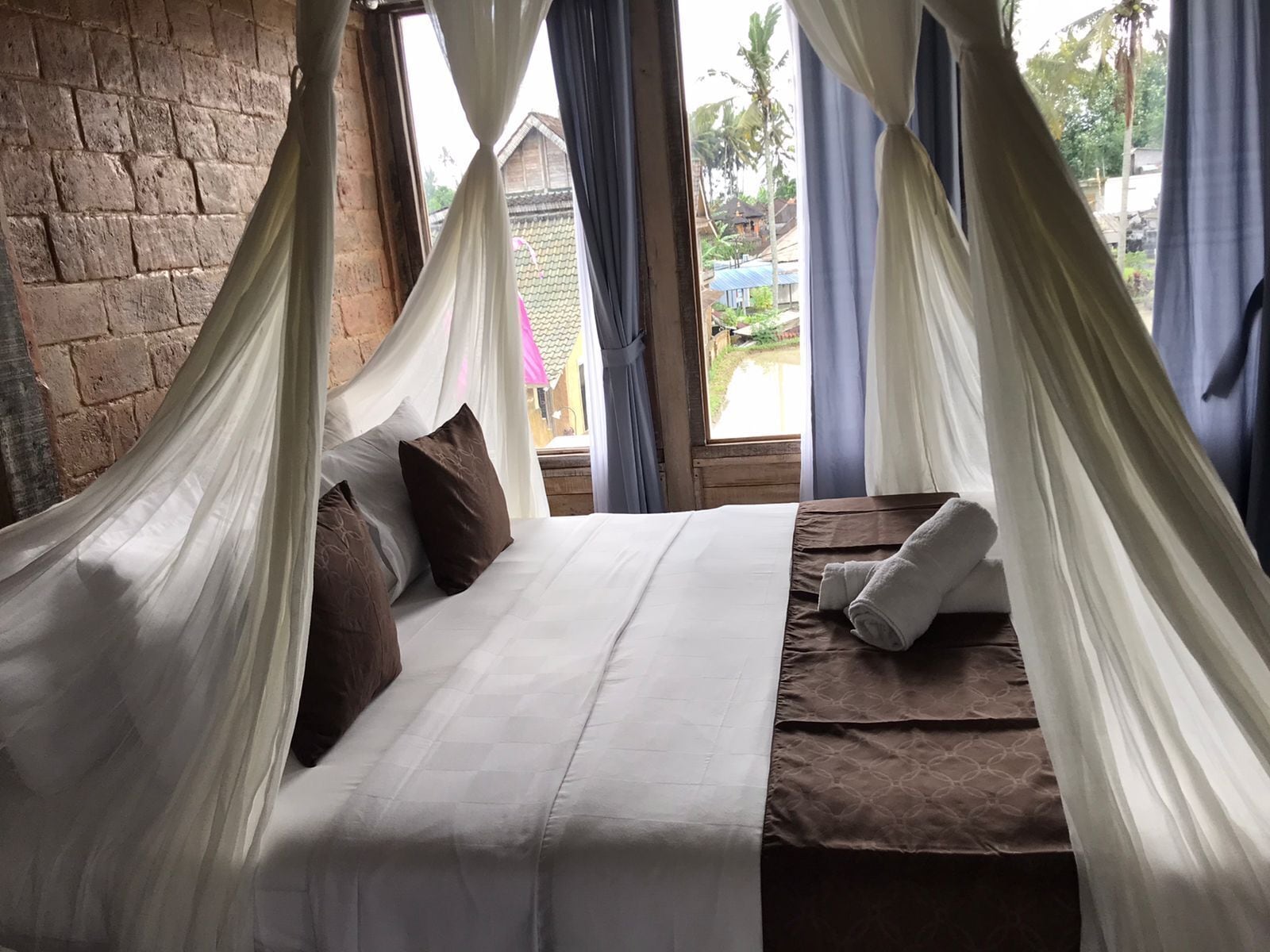 A bed with a canopy, pillows, and a towel.