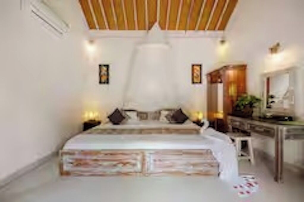 A bedroom with a bed, bedside tables, a desk, and a mirror.