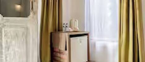 A room with a white door, a small cabinet, and a window with curtains.