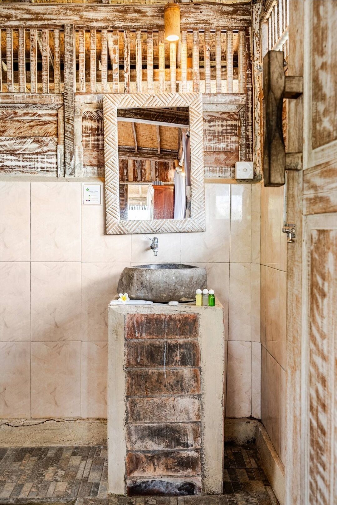 A rustic bathroom with a stone sink, wooden beams, and a mirror.