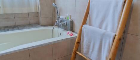 A bathroom with a bathtub, a wooden ladder, and a towel rack.