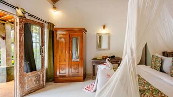 Una habitación con cama, armario de madera, escritorio y lámpara de pared.