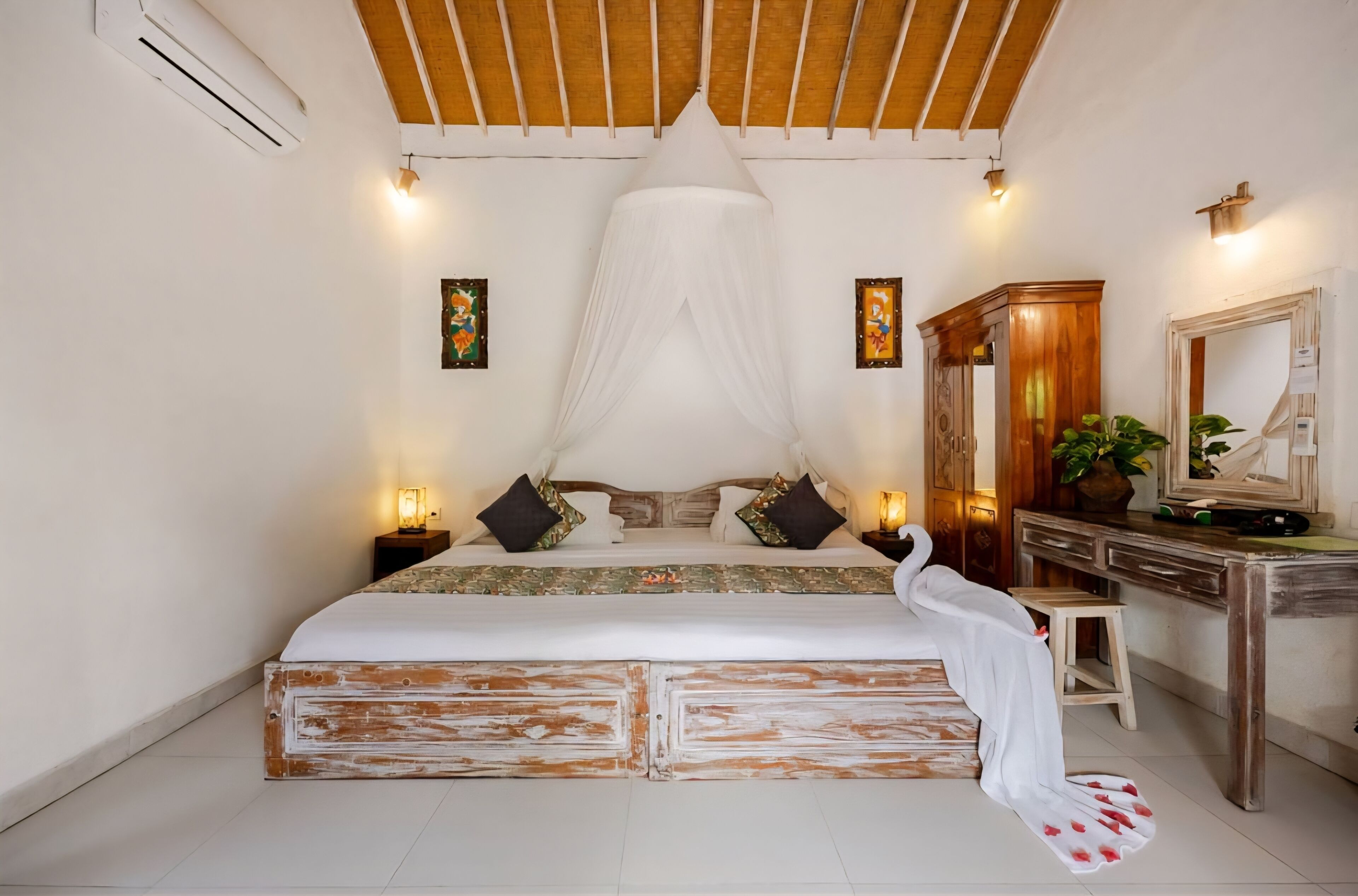 Un dormitorio con cama con dosel, mesitas de noche con lámparas, un escritorio de madera y un espejo.