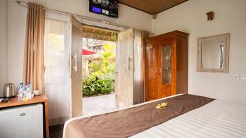 Habitación de hotel con una cama, un armario de madera, un escritorio con hervidor, un televisor y vistas al exterior.