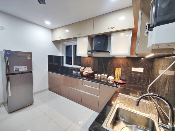 A modern kitchen with stainless steel appliances, a black countertop, and a built-in sink.