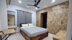Un dormitorio con una cama de madera, un armario, un ventilador de techo y un espejo.