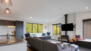 A modern living room with a sofa, a fireplace, and a television. - Private Sauna & Cold Plunge | Spacious, Close To Town | Queenstown Hill Location (Queenstown)