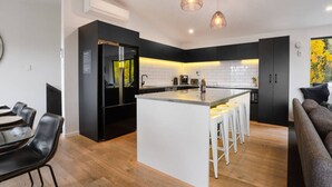 A modern kitchen with a central island, black cabinetry, and pendant lighting. - Private Sauna & Cold Plunge | Spacious, Close To Town | Queenstown Hill Location (Queenstown)