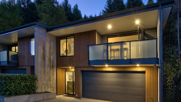 A modern two-story house with a garage, large windows, and a balcony. - Private Sauna & Cold Plunge | Spacious, Close To Town | Queenstown Hill Location (Queenstown)