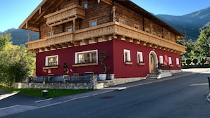 Una cabaña de madera tradicional con fachada roja, balcones y base de piedra.