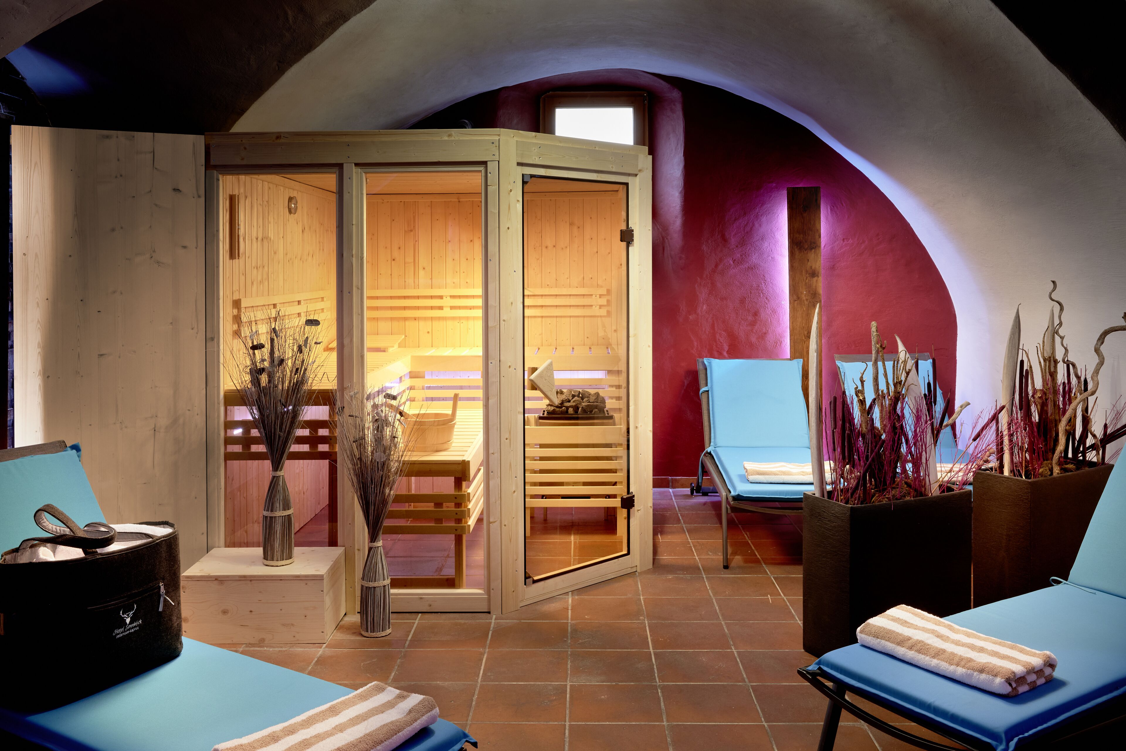 Sala de sauna com bancos de madeira, mesa de massagem e cadeira de massagem.