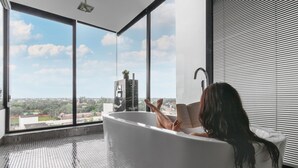 A woman relaxing in a large bathtub with a city view. - Hotel Vellita Siem Reap (Siem Reap)