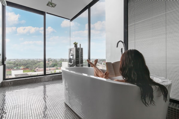 A woman relaxing in a large bathtub with a city view. - Hotel Vellita Siem Reap (Siem Reap)