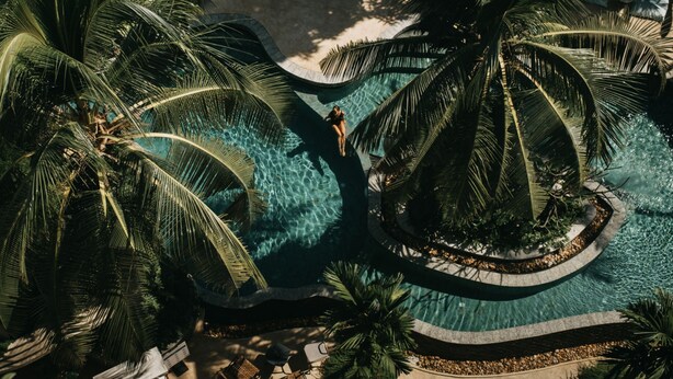 An aerial view of a resort with a central pool surrounded by palm trees and a circular water feature. - Hotel Vellita Siem Reap (Siem Reap)