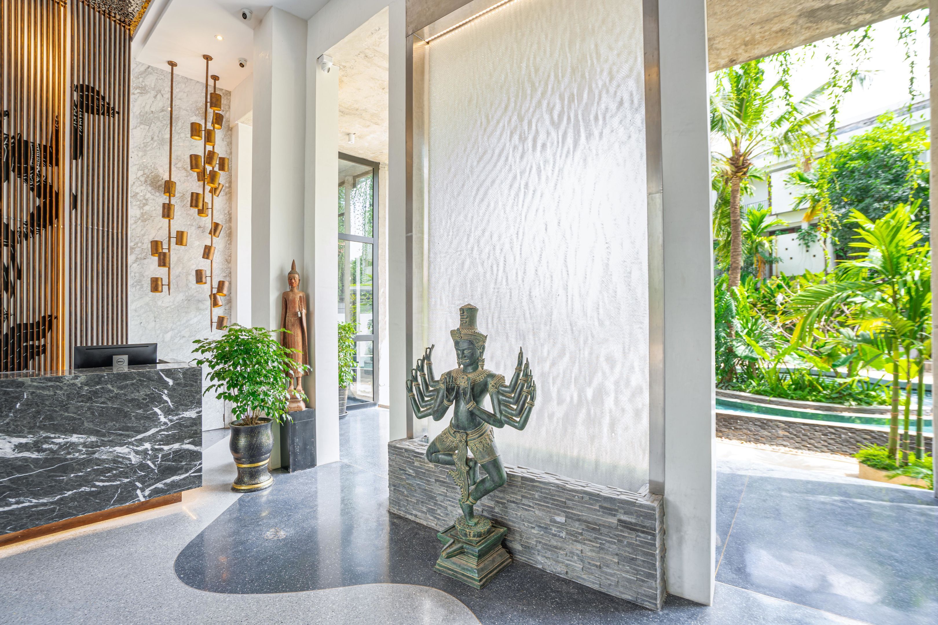 A reception area with a marble counter, a statue, and a plant.