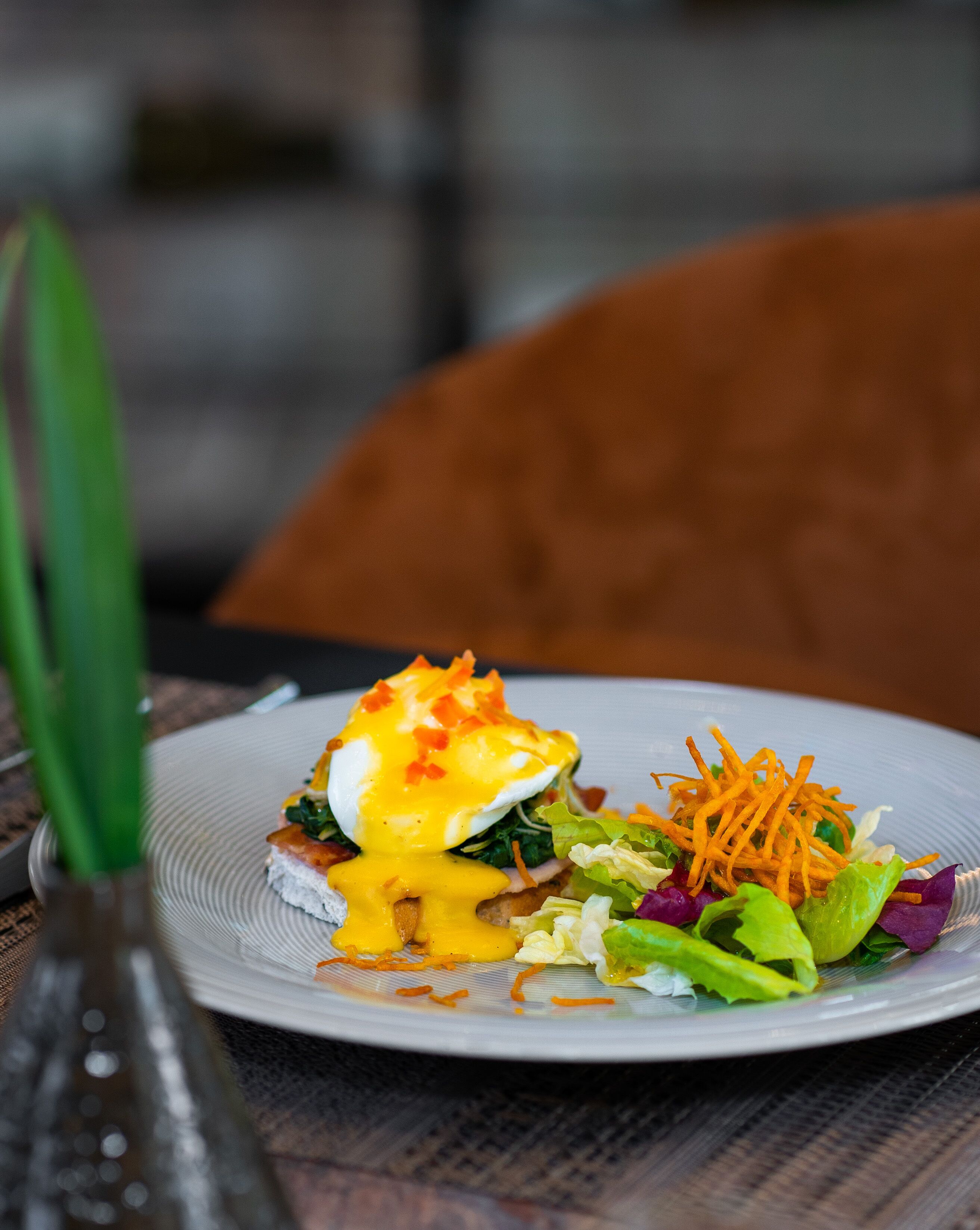 A plate of food with a poached egg, greens, and shredded carrots.