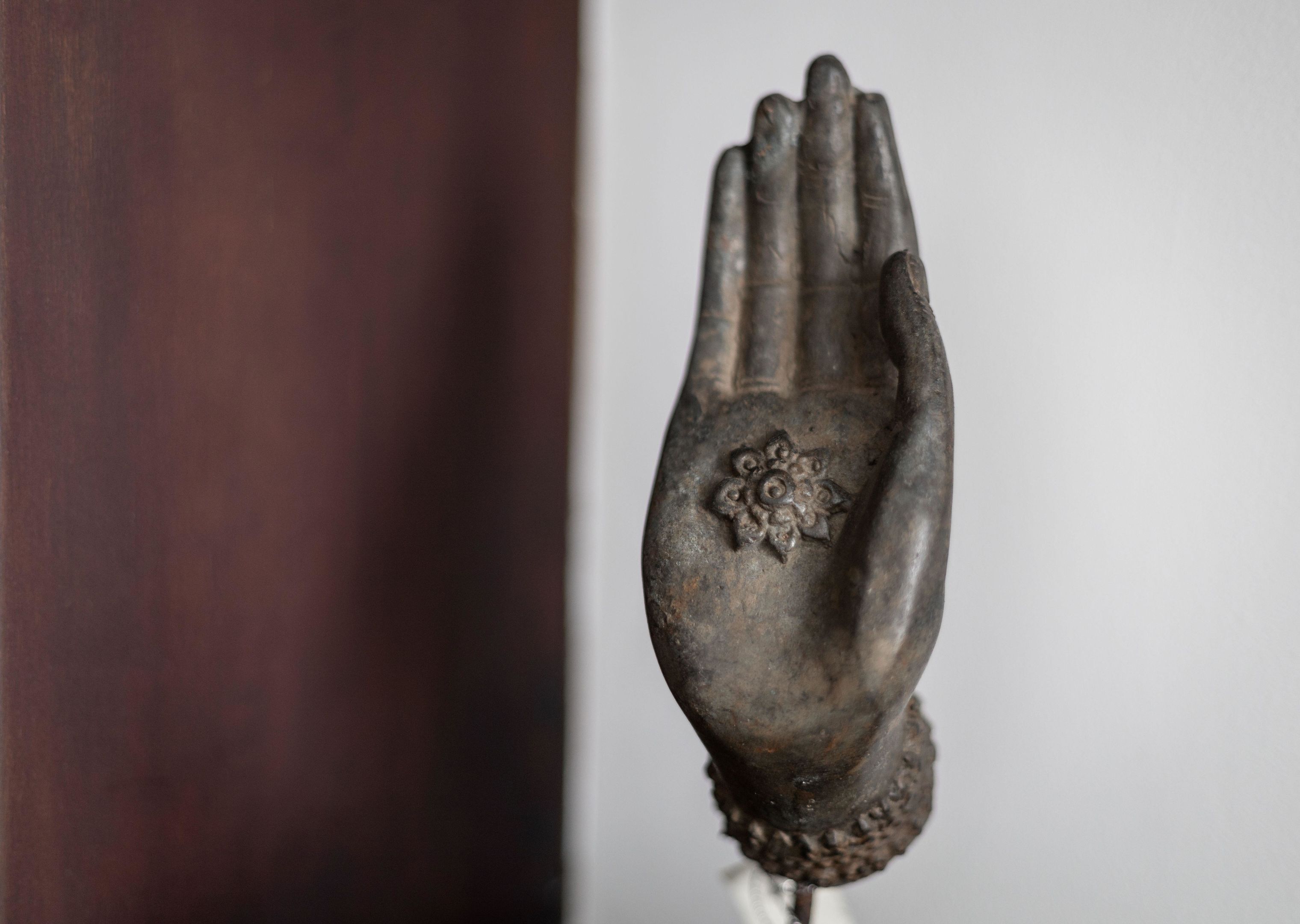 A hand-shaped sculpture with a floral design, mounted on a base.