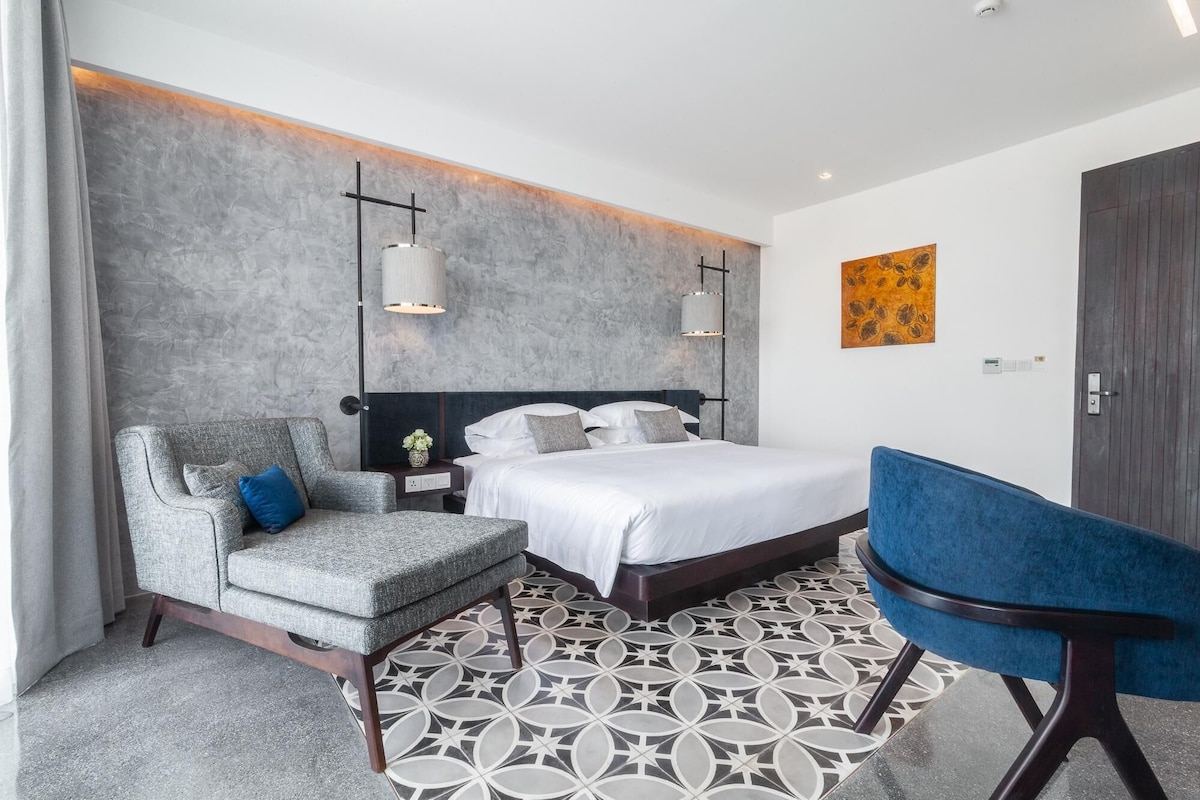 Een moderne hotelkamer met een bed, een bureau, een stoel en een decoratieve wand.