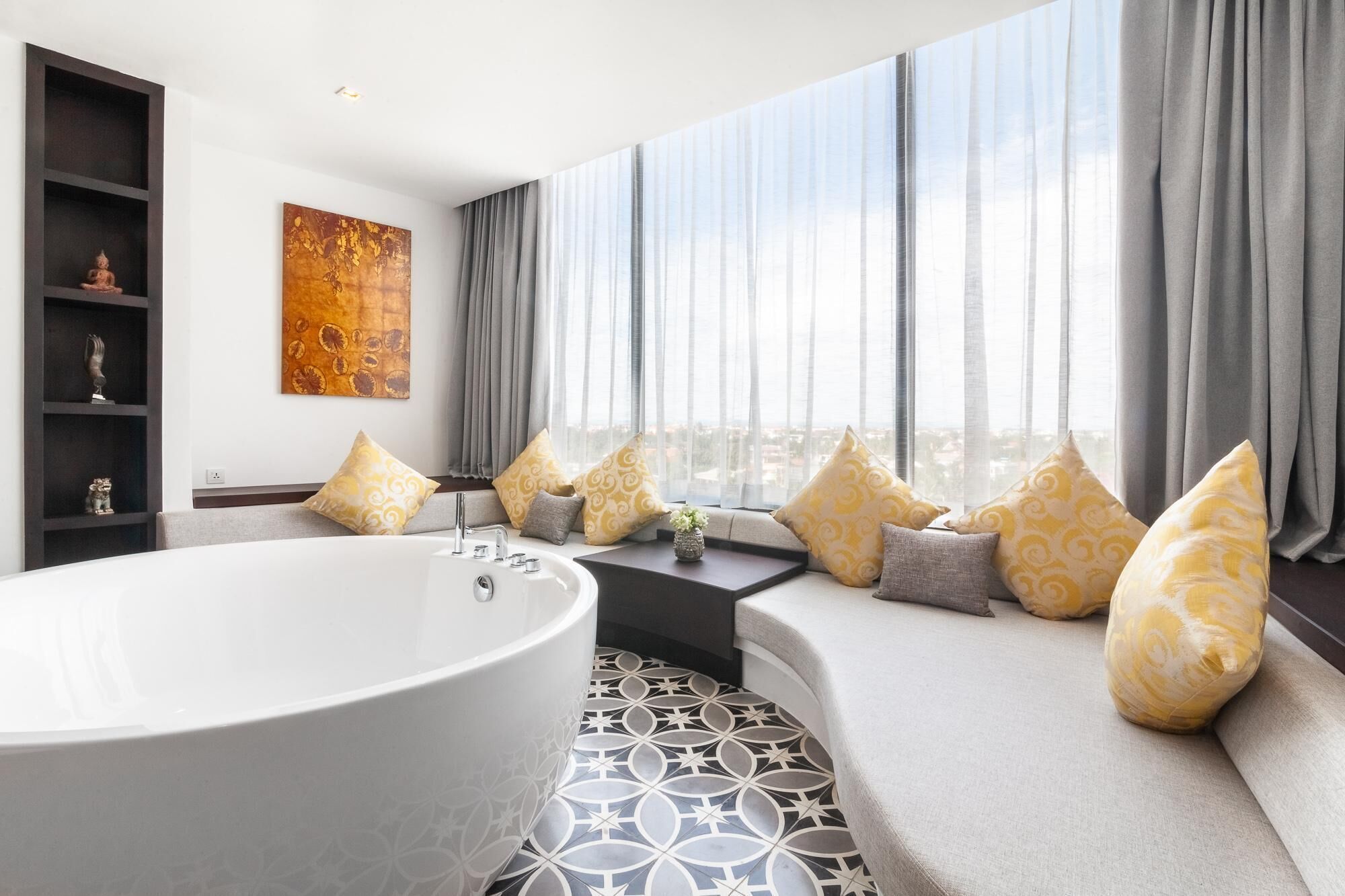 Een moderne badkamer met een vrijstaand bad, een groot raam met gordijnen en uitzicht op de stad.